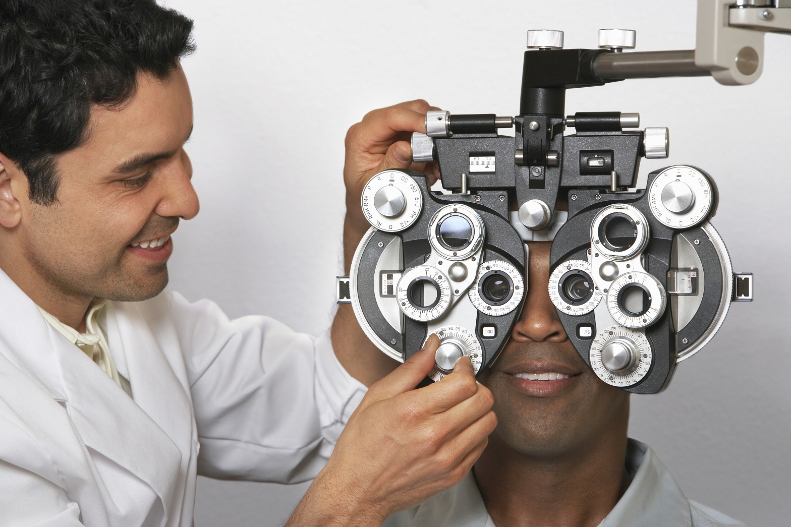 Male optometrist with phoropter while examining patient